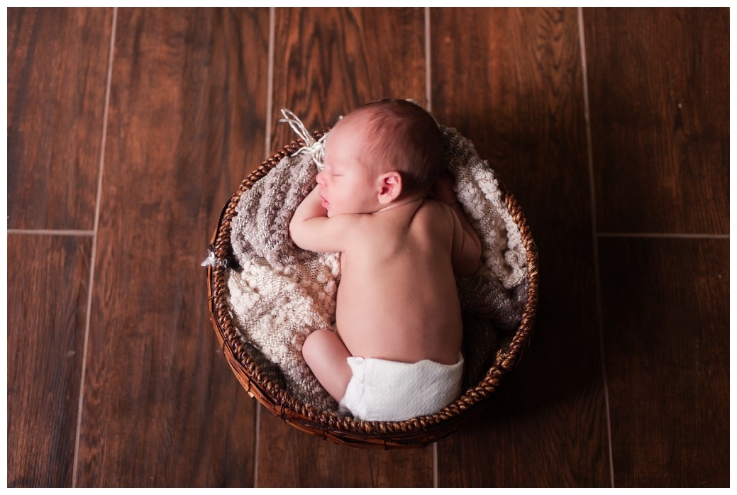 Newborn baby on wood floor in basket