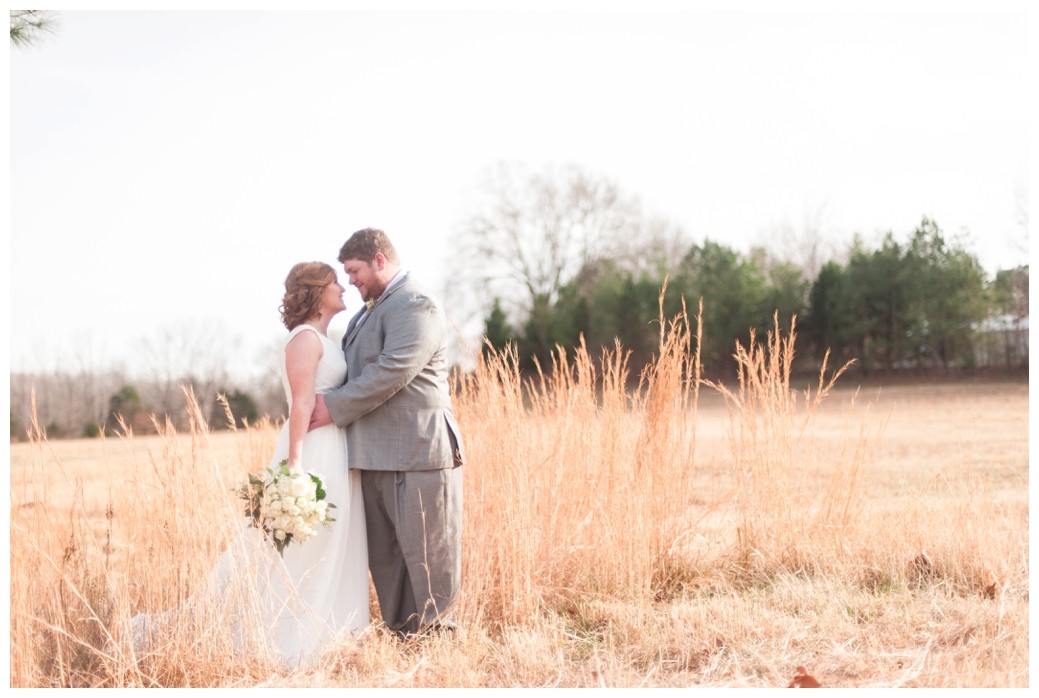 bride and groom in field standing in tall grass looking at one another