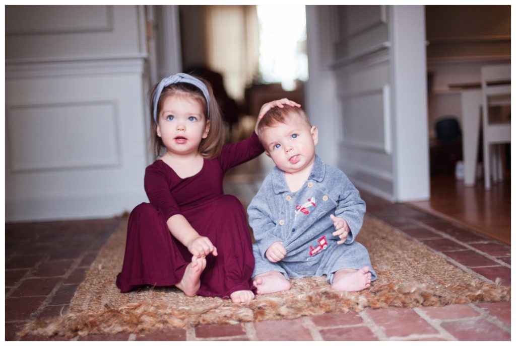 six month session little boy and sister sitting on rug