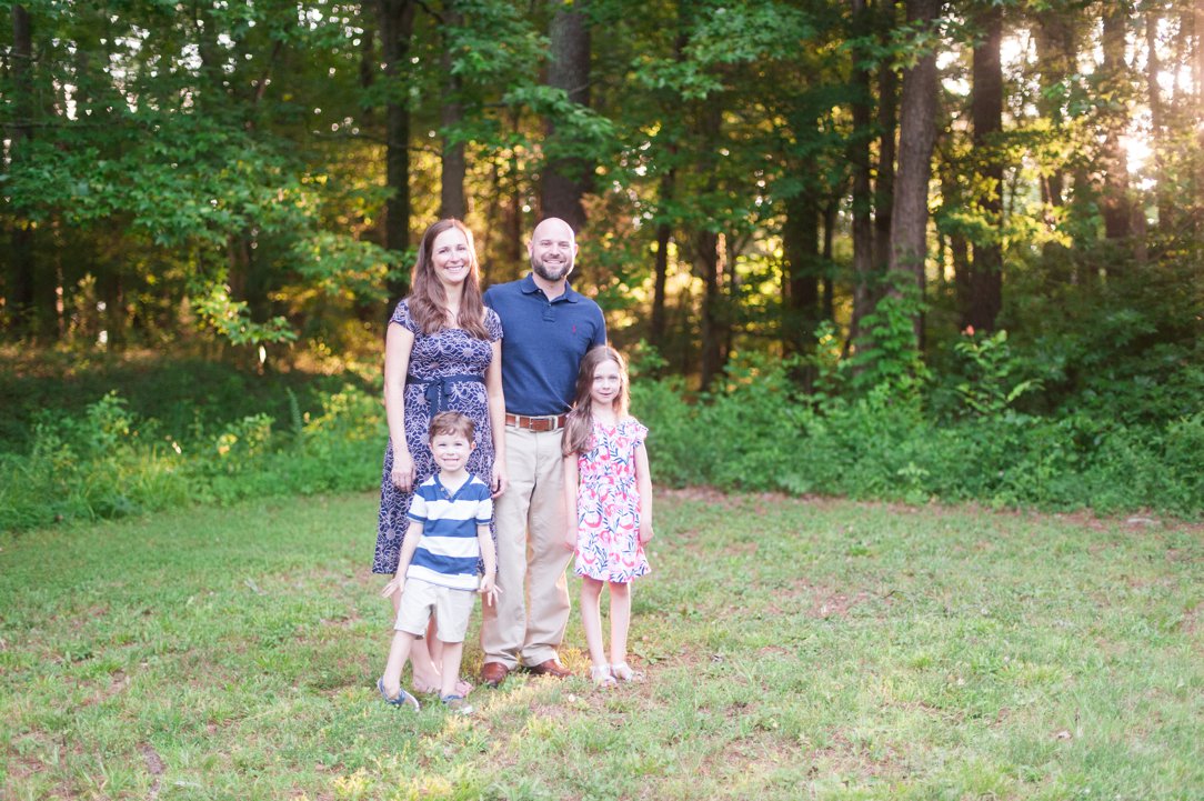 the lewis family standing near woods with light coming in