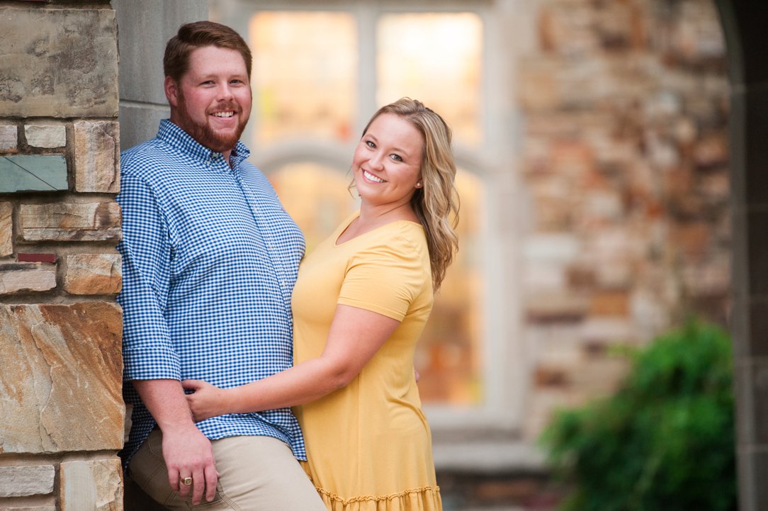 Rhodes College Engagement smiling at camera by brick wall