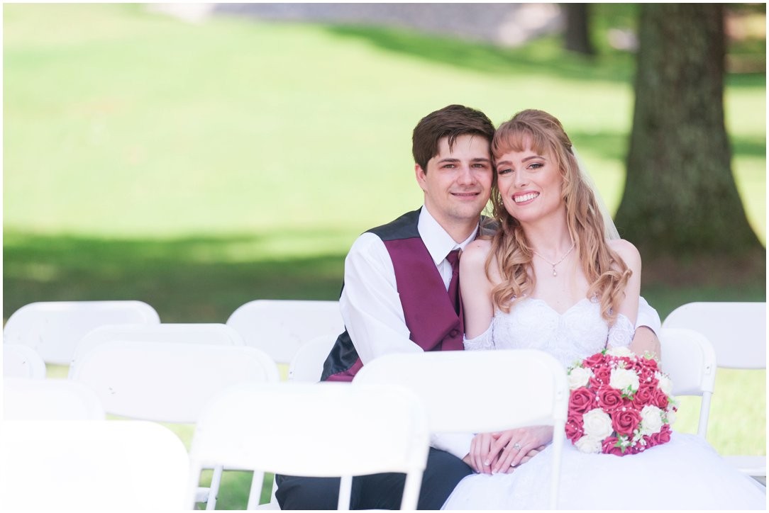 Summer lakeside Wedding couple sitting in ceremony site