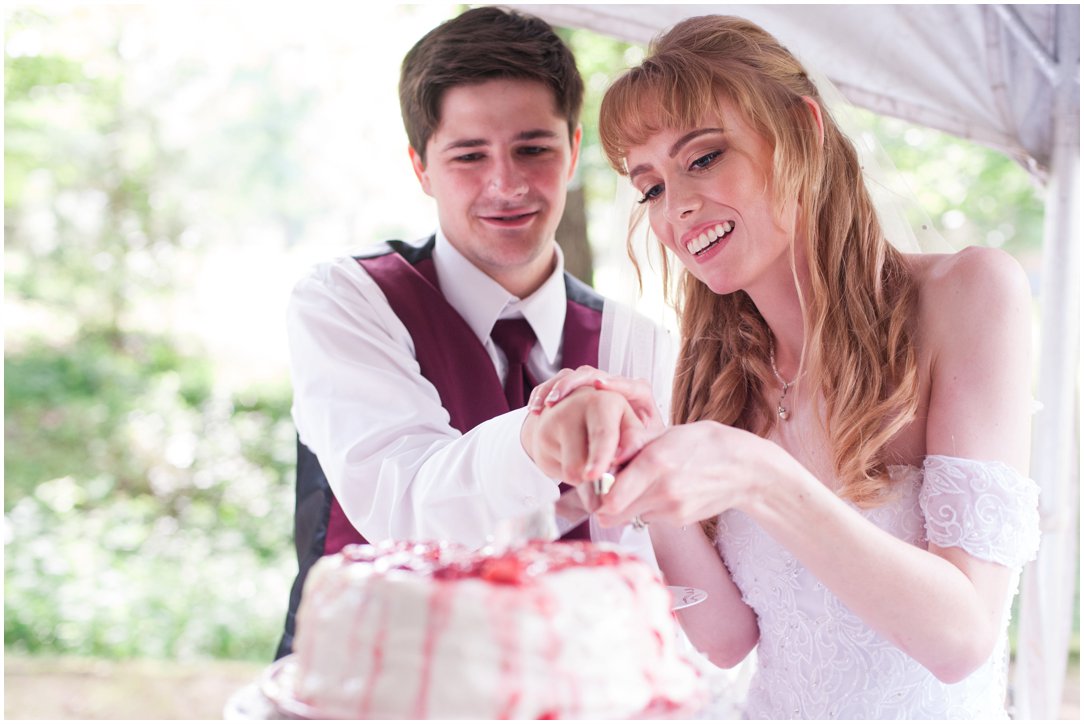 Summer lakeside Wedding couple cutting cake