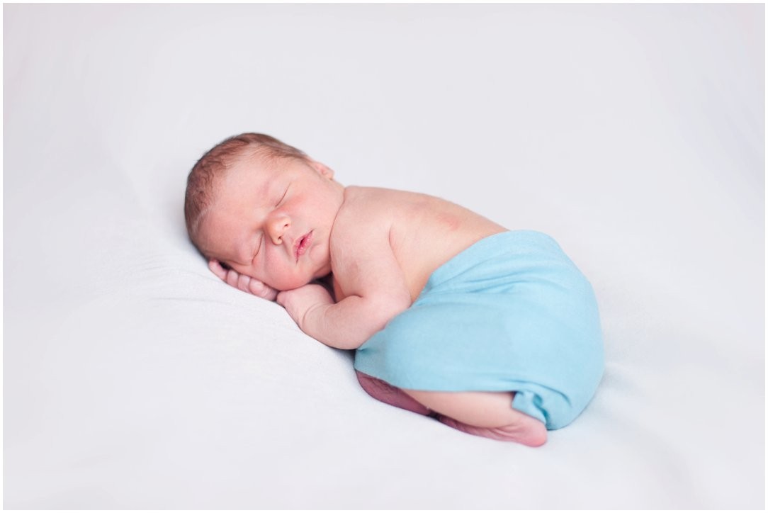 Newborn in blue curled up