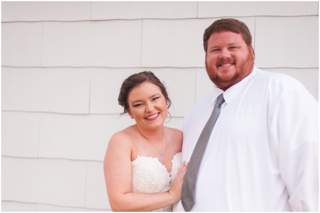 bride and groom looking at camera in front of white wall