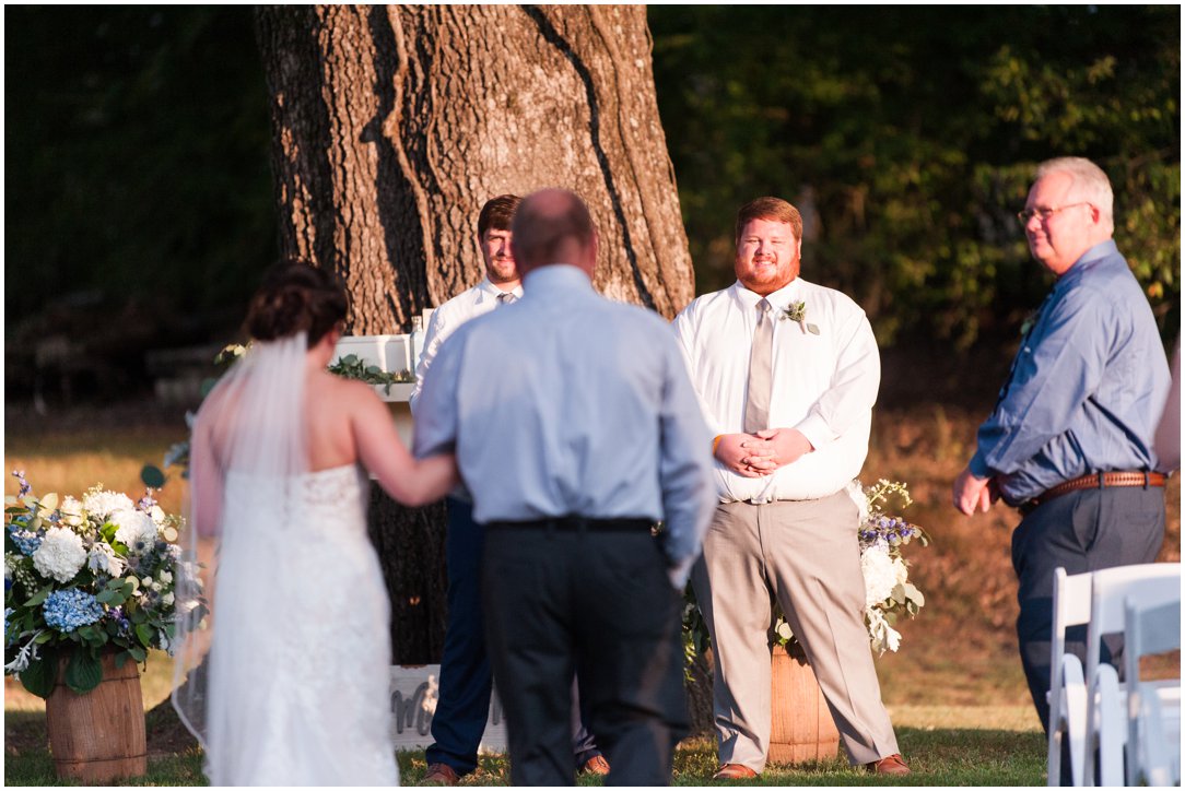 groom looking at bride and dad coming down aisle