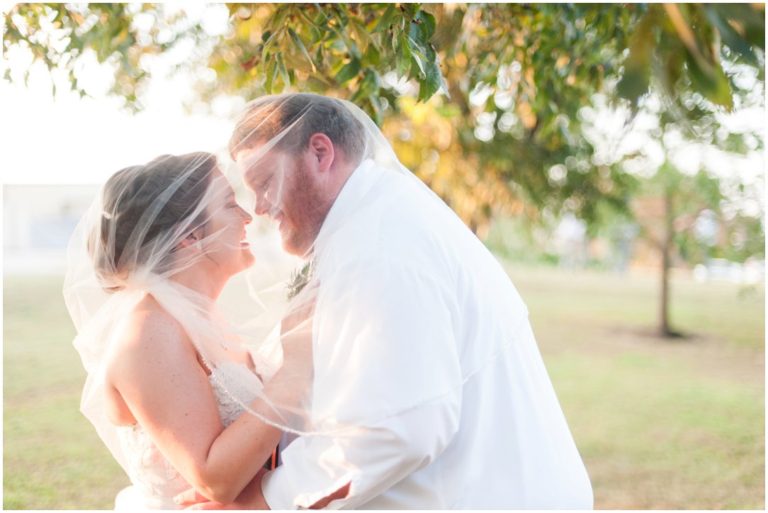 bride and groom smiling under veil