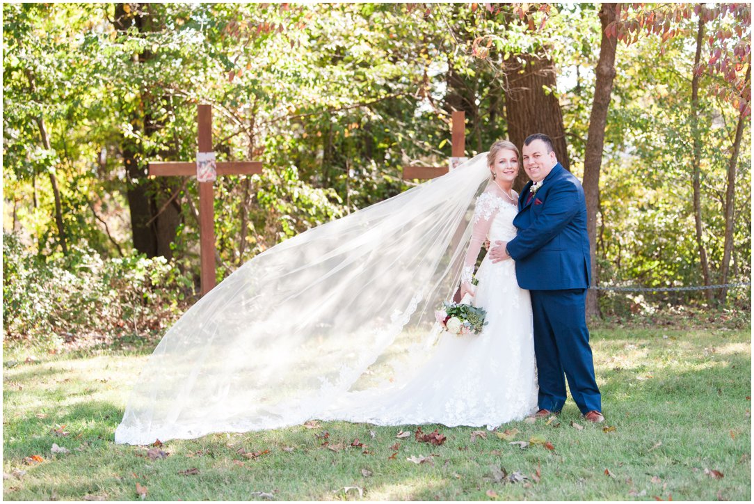 bride with long veil outside with groom