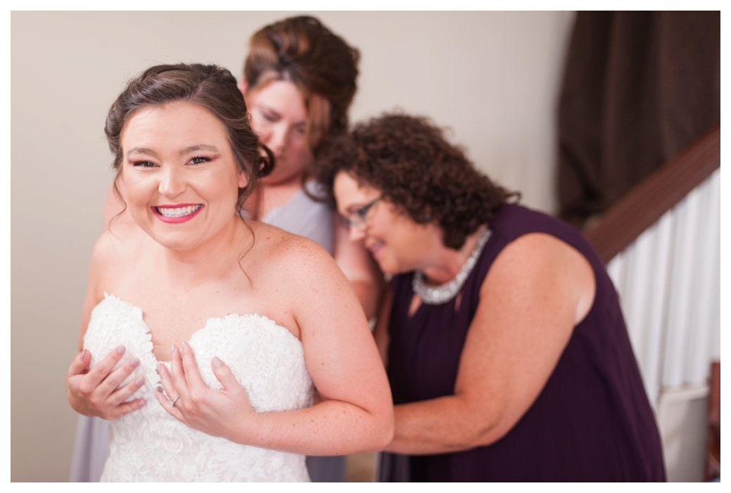 bride getting into dress with mom