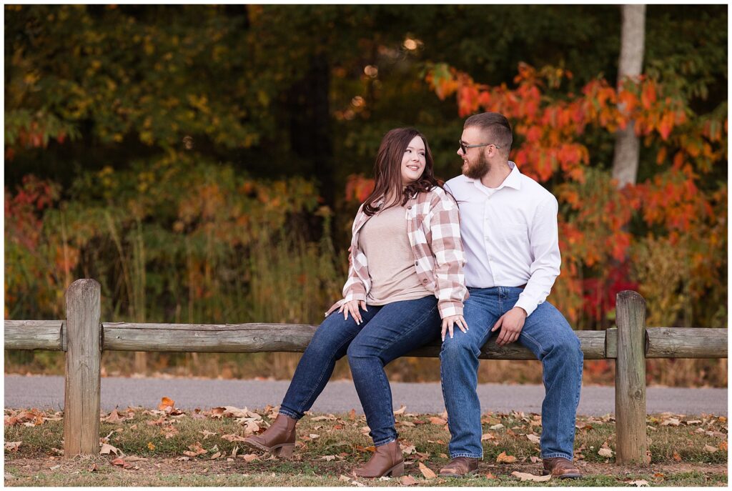 Couple on fence at engagement session at park